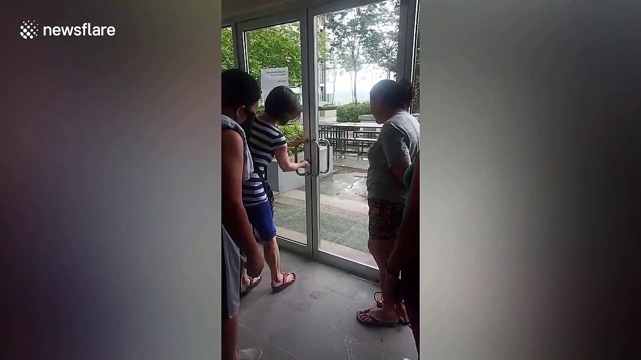 Filipina woman struggles to open door while friends walk through section without glass