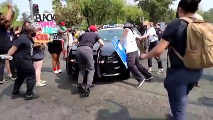 Un manifestant tente de bloquer une voiture de police