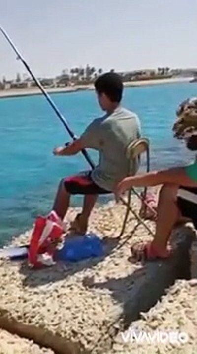 Il se moque de son ami, qui pêche à la ligne pour la première fois