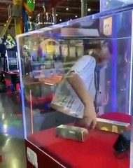 Download Video: Elle réussit à faire sortir cet objet volumineux d’une vitrine à travers un trou, sans rien casser