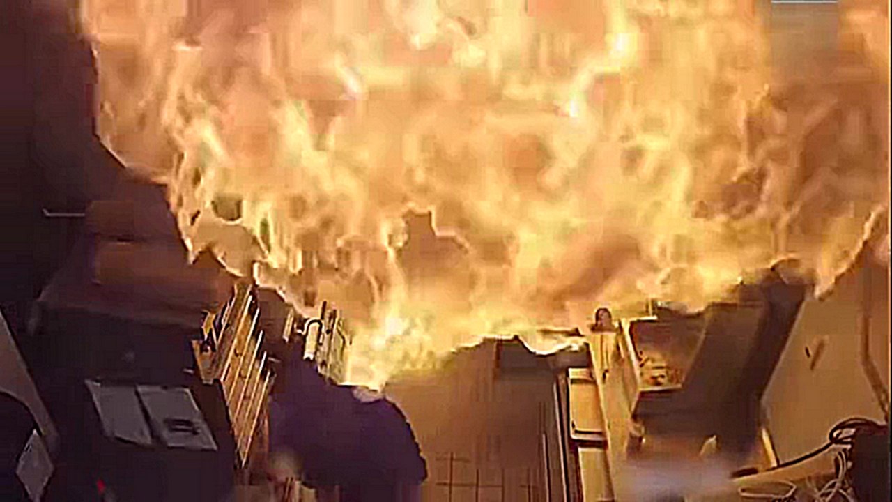 Un cuisinier jette un saut d'eau sur un feu de friteuse