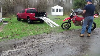 Il tente de charger sa moto à l'arrière du pick-up mais oublie de freiner