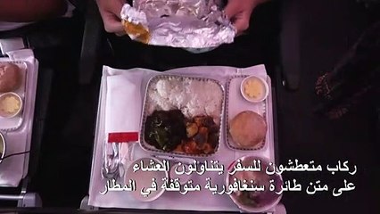 ركاب متعطشون للسفر يتناولون العشاءعلى متن طائرة سنغافورية متوقفة في المطار
