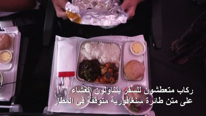 ركاب متعطشون للسفر يتناولون العشاءعلى متن طائرة سنغافورية متوقفة في المطار
