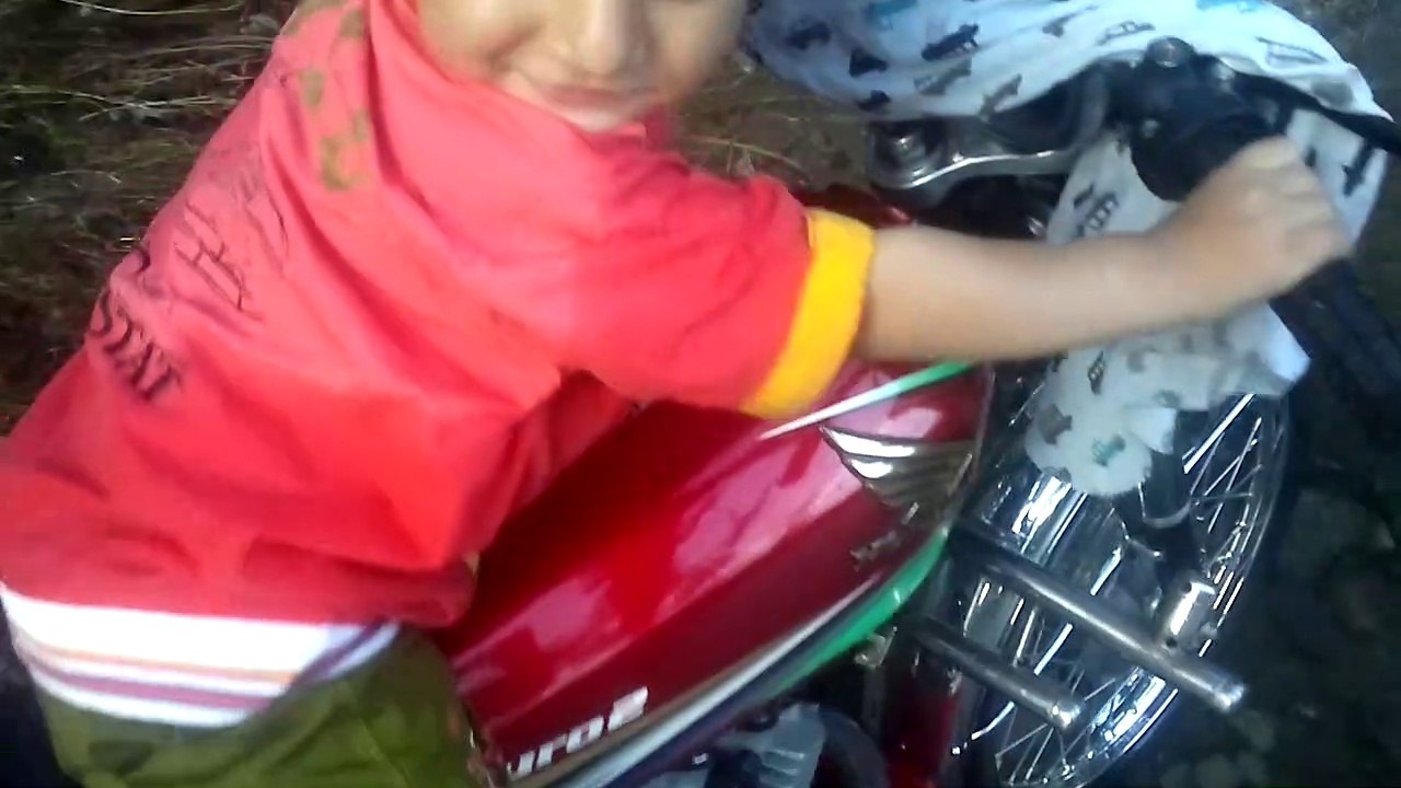 Cute little boy making spout in water from bike