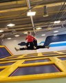Dad Holds Toddler's Feet in Hands While Jumping on Trampoline in Jumping Park