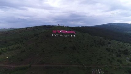Bir vatandaş, tepenin yamacındaki rengi solan dev Türk bayrağını boyuyor