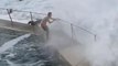 Huge Wave Comes Crashing Down on Guy Standing Near Roped Fence at Seashore