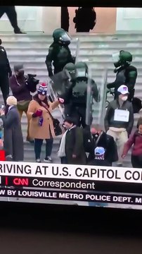 Un policier aide une manifestante pro Trump à descendre des marches