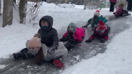 Kids enjoy icy slide downhill on snow day