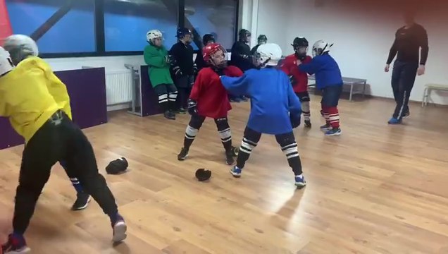 Des enfants s'entrainent au combat pendant un cours de hockey sur glace