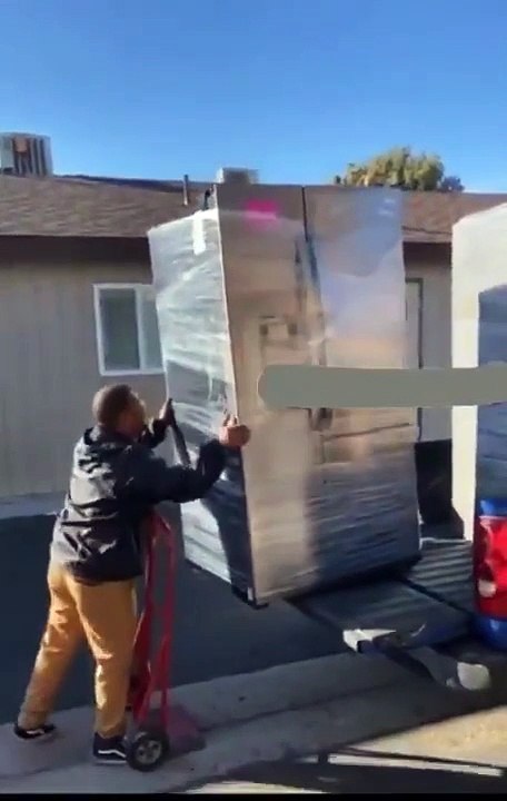 Il met un frigo énorme sur un diable avec une méthode un peu bizarre