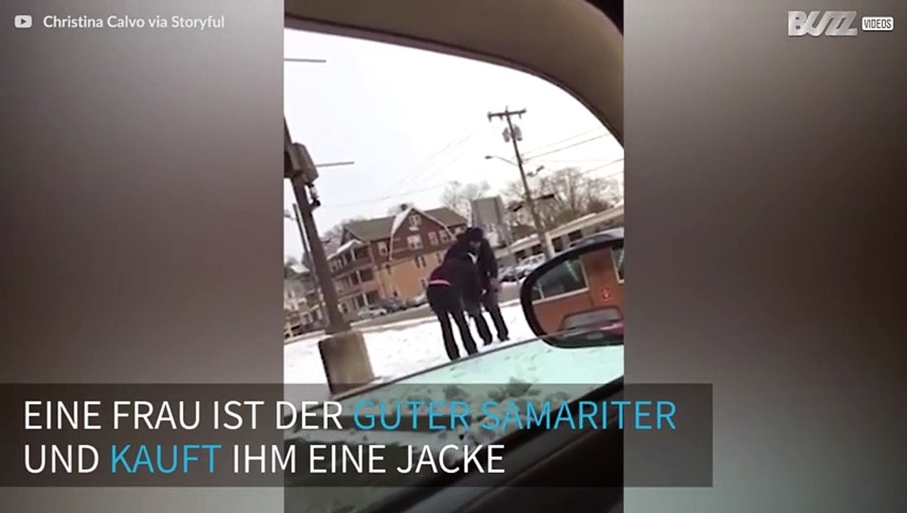 Eine Frau gibt einem Mann einen Mantel, nachdem sie ihn in der Kälte sieht.