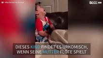 Lustiges Kleinkind muss immer lachen wenn Mutter Flöte spielt