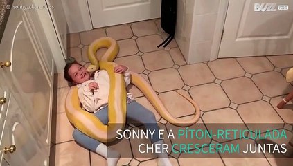 Menina brinca com píton gigante no chão da cozinha