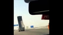 Un camion avec la remorque levée passe sous un pont sur l'autoroute