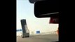 Un camion avec la remorque levée passe sous un pont sur l'autoroute