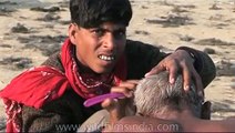 Hindu pilgrim has his head shaved during Kumbh Mela
