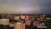 Lightning streaks across the sky behind a rainbow