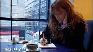 JK Rowling writing at coffee table (2000)