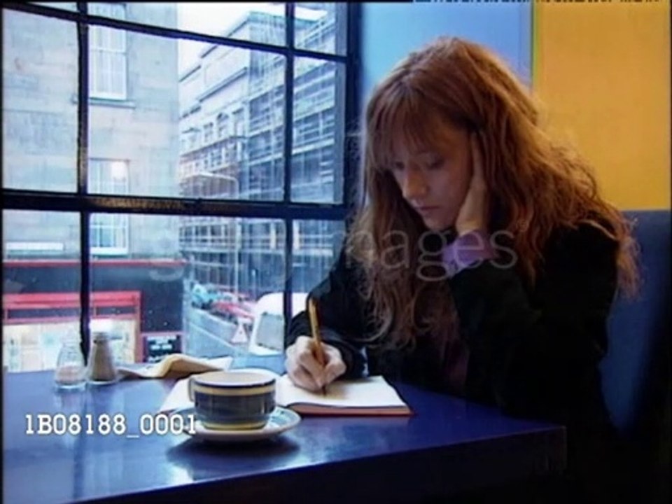 JK Rowling writing at coffee table (2000)