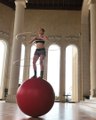 Woman Balances On Giant Yoga Ball And Performs With Multiple Hula Hoops