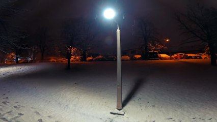 A lonely street lamp standing in park during snowy winter night.