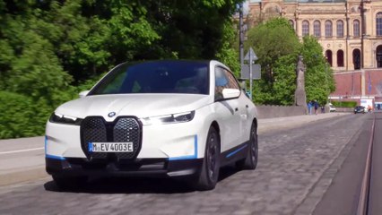 The first-ever BMW iX in White Driving in the city