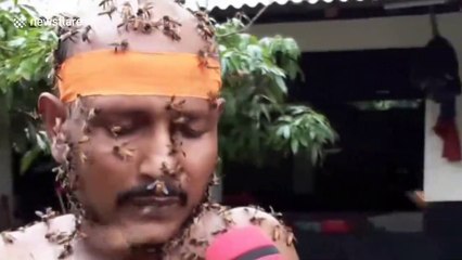 Des milliers d'abeilles recouvrent cet homme qui joue de la flute