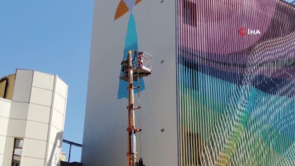 Kafasını kaldırıp vincin tepesinde elinde fırçayla görenler gözlerini alamıyor