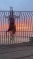 Guy Performs Upside Down Push-Ups And Pull-Ups While Hanging On Grill Wall During Sunset