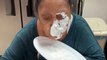 Person Playfully Pranks Elderly Woman by Tricking Her Into Smearing Whipped Cream on Her Face