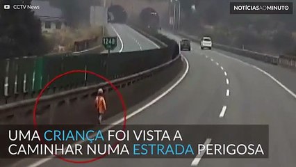 Criança pequena caminha sozinha numa estrada perigosa