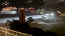 Floodwaters carry trash cans across DC street