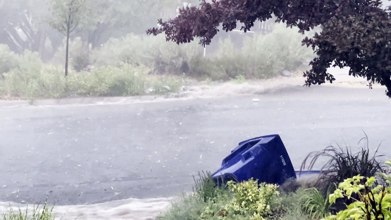 Garbage Cans Float Down Street During Flood