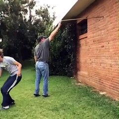 Boy Jumps Off Wall Over Stick Held By His Dad
