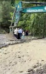 Çayın karşısına geçmeye isteyen vatandaşları kepçe taşıdı