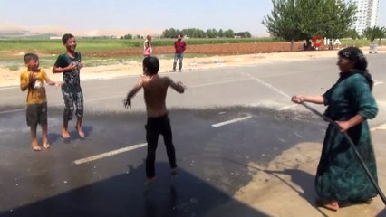 Sıcaktan bunalan çocuklarını hortumla su sıkarak serinletti