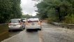 Motorists pass stranded vehicle in flooded road