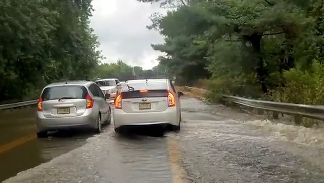Motorists pass stranded vehicle in flooded road
