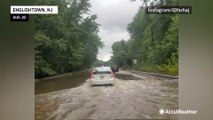 Motorists pass stranded vehicle in flooded road