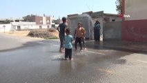 Sıcaktan bunalan çocuklarını hortumla su sıkarak serinletti