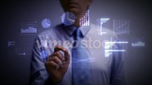 A_businessman_working_on_a_blue_holographic_interface,_touching_a_hologram_showing_a_visual_screen_with_computer_and_business_ic