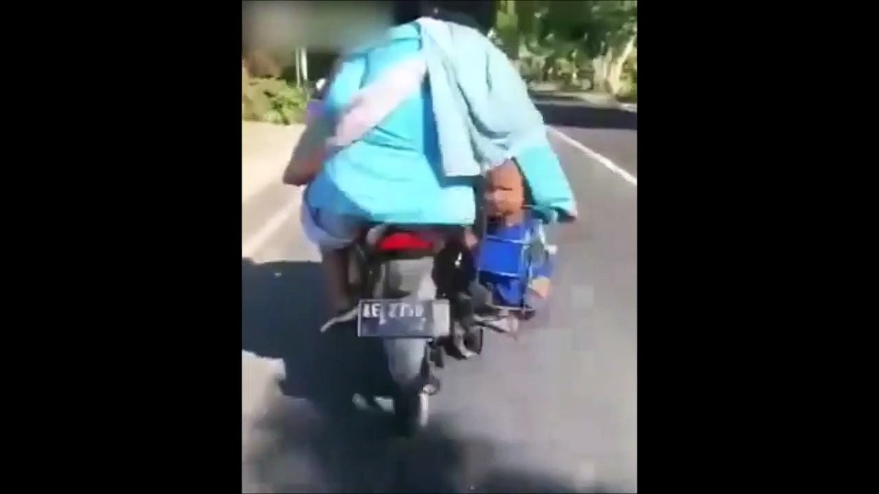 Ces parents transportent leur enfant dans le porte bagage de leur moto... Allez, à l'école