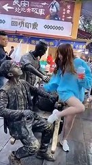 Elle vient donner à boire à un homme statue d'une façon très bizarre...