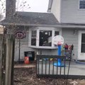 Kid Throws Ball in Basket While Standing on Trampoline on Opposite End