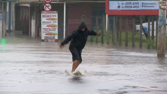Homem surfa em rua alagada em Vila Velha