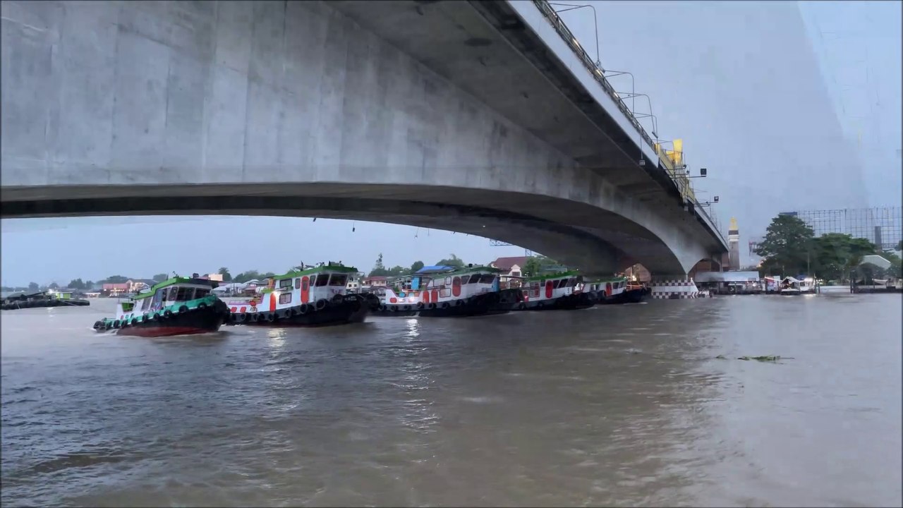 5 Tugboats pulling a huge barge at Pak Kret Chao Phraya river in Thailand
