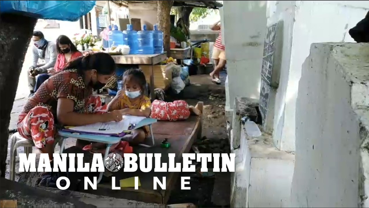 Candles and flowers vendor assists her daughters in answering their modules while waiting for customers in Davao City’s Roman Catholic Cemetery