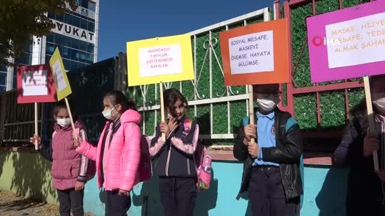 Öğrenciler ellerinde dövizlerle Covid-19'a dikkat çekmek için etkinlik düzenledi